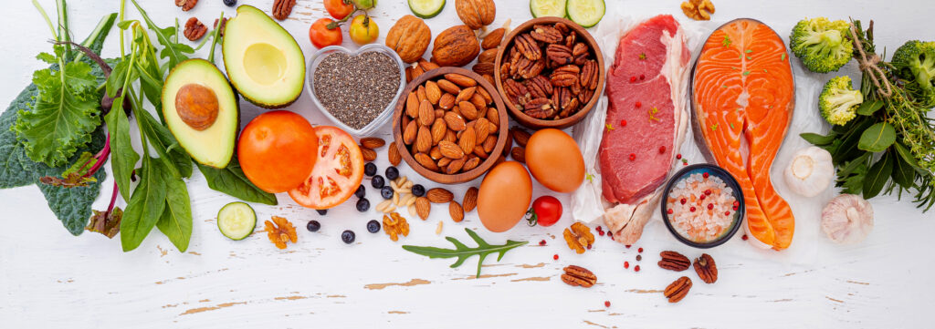 healthy keto foods on a white wooden table top