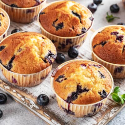6 Low-carb blueberry muffins on a tray with blueberries scattered around