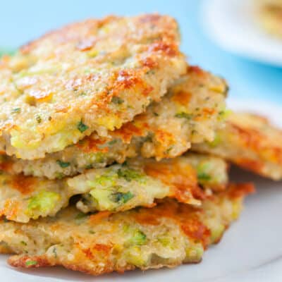 A stack of 4 Low-Carb Broccoli Fritters with Cheddar Cheese on a white dinner plate