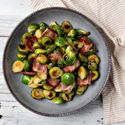 Fried brussel sprouts with bacon on a blue plate.
