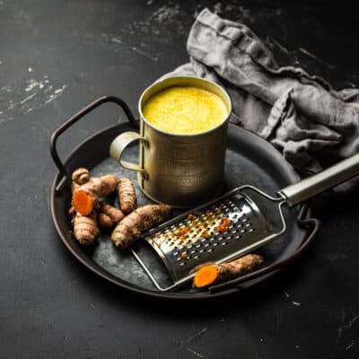 Low carb golden milk with turmeric on a tray in a rustic cup