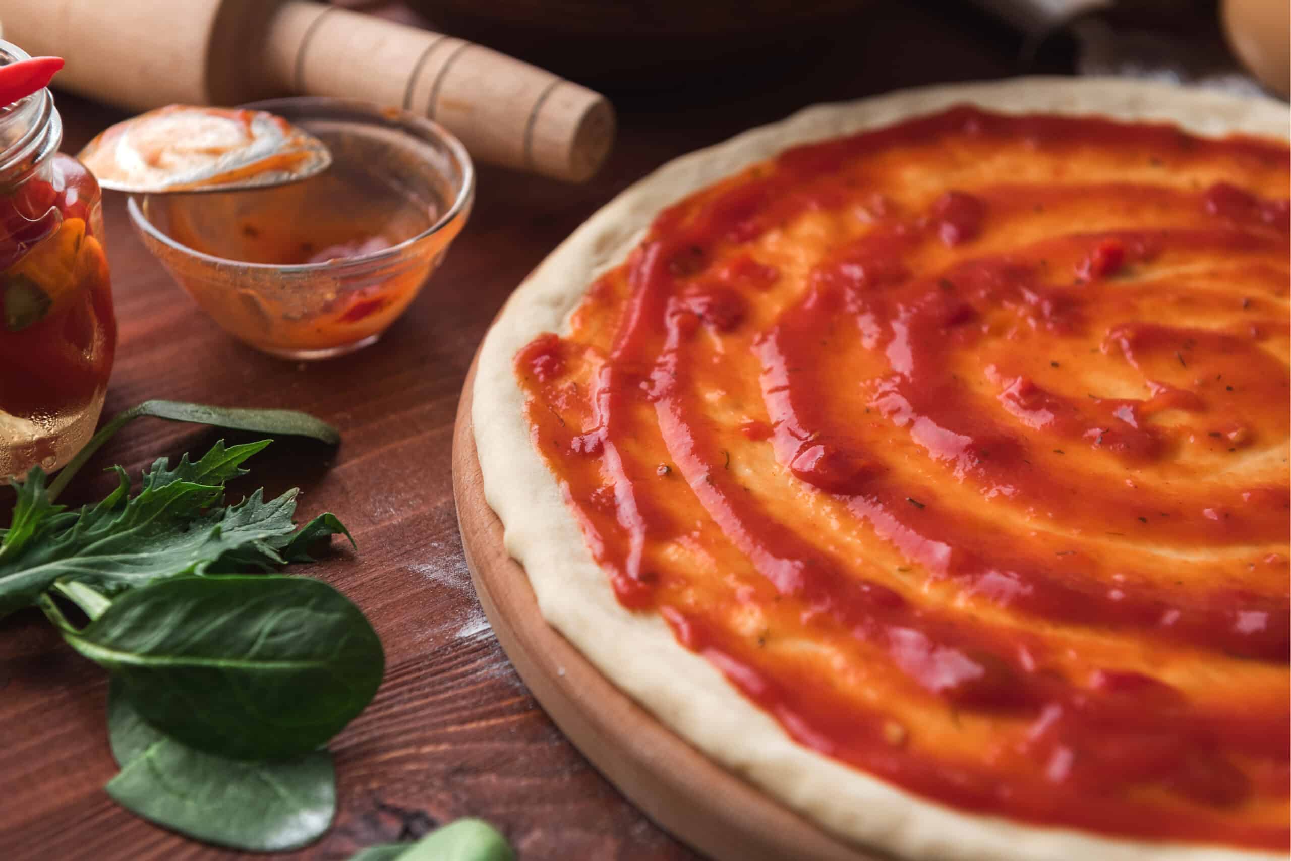 close up image of a low carb pizza base with low carb pizza sauce on top