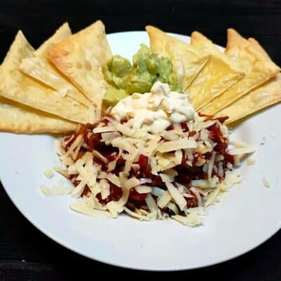 low-carb beef chilli with edame tortilla chips on a white plate