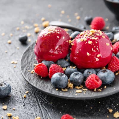 low carb berry sorbet on a black plate with blueberries and raspberries