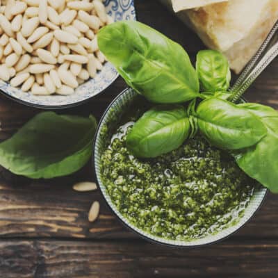 home made green pesto in a bowl with fresh basil, pine nuts and parmesan cheese